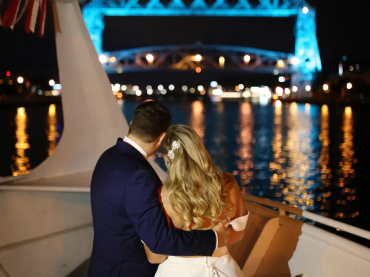 bride and groom on a boat looking at a bridge