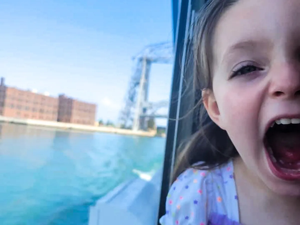 a little girl sitting in front of a body of water