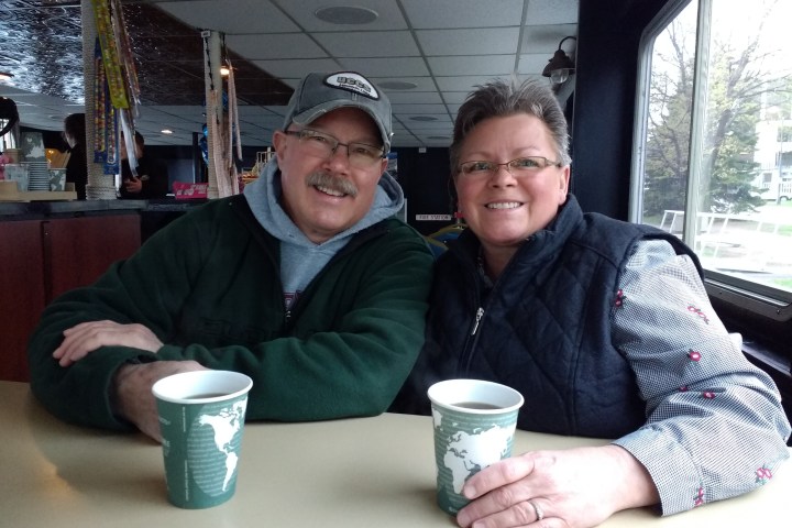 a man and a woman sitting at a table with a cup of coffee