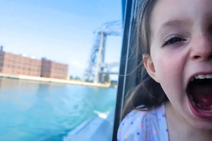 a little girl sitting in front of a body of water