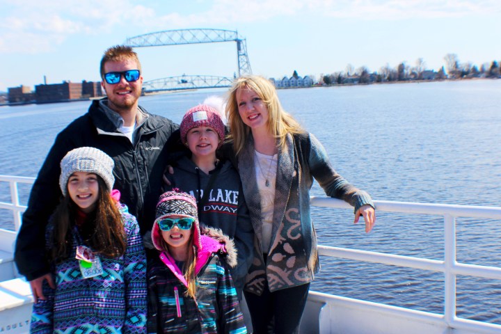 family on a boat in front of the Aerial Lift Bridge