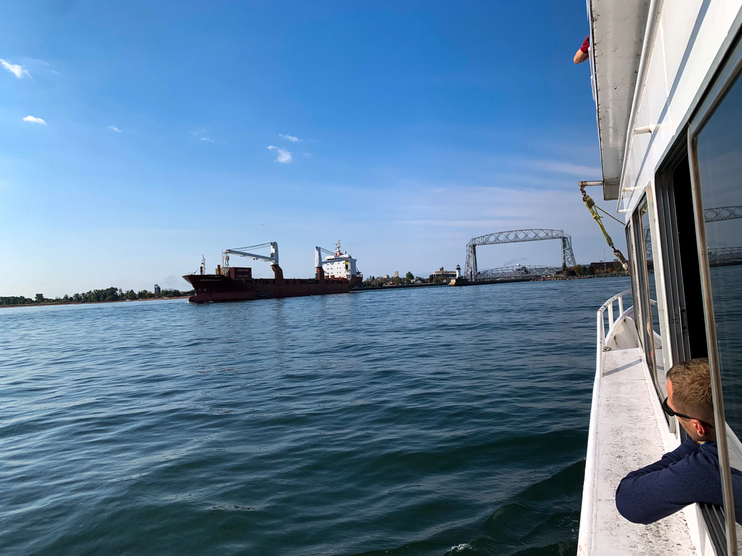 Guy looking out window of boat at a freighter on the Great Lakes