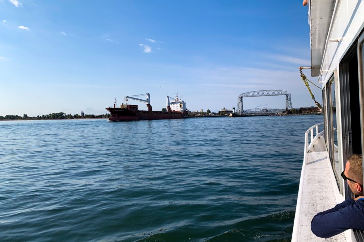 a person looking out the window of the Vista Star watching a freighter go under the lift bridge