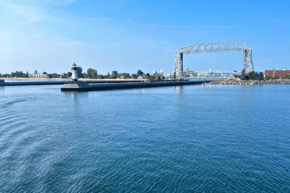 Aerial lift bridge over a calm blue waterfront under a clear sky.